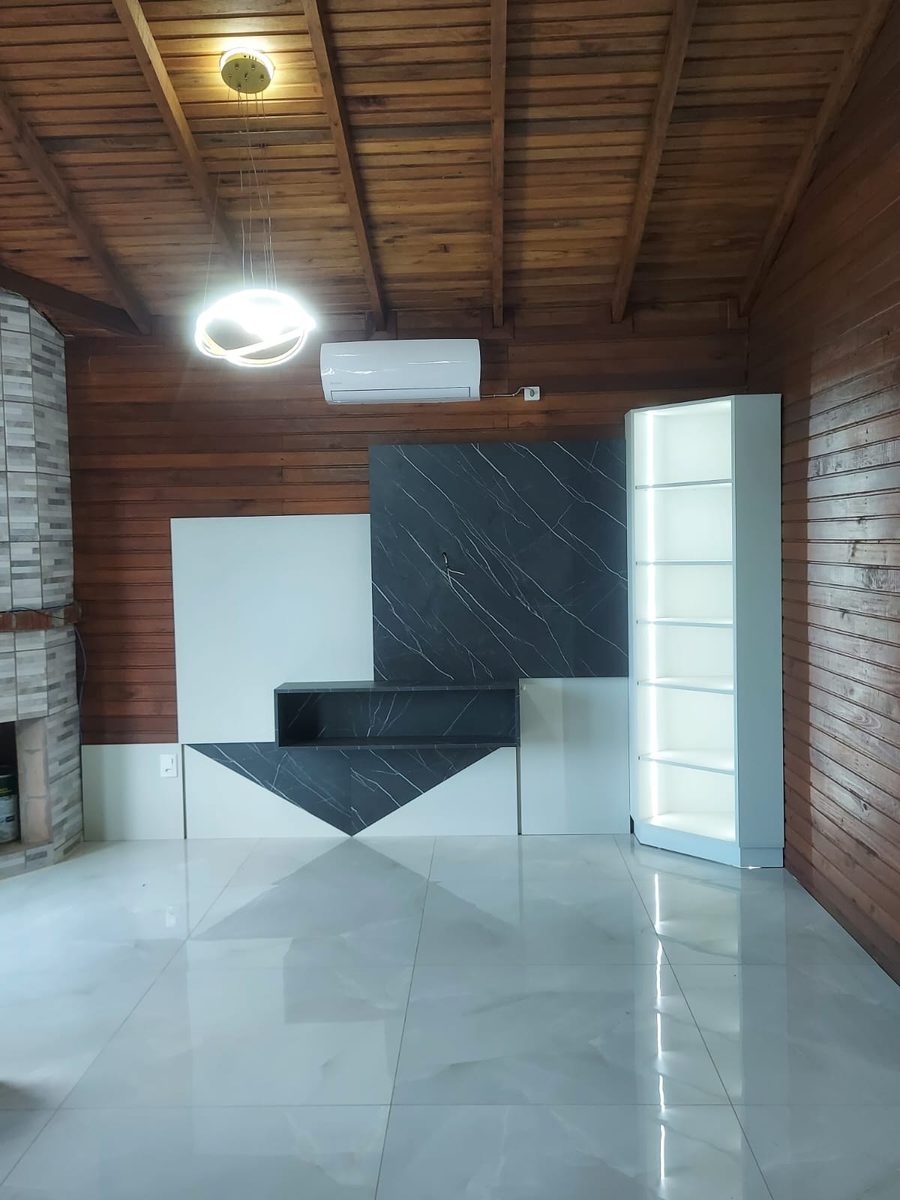 Sala com painel de TV em mármore, nicho suspenso e estante iluminada