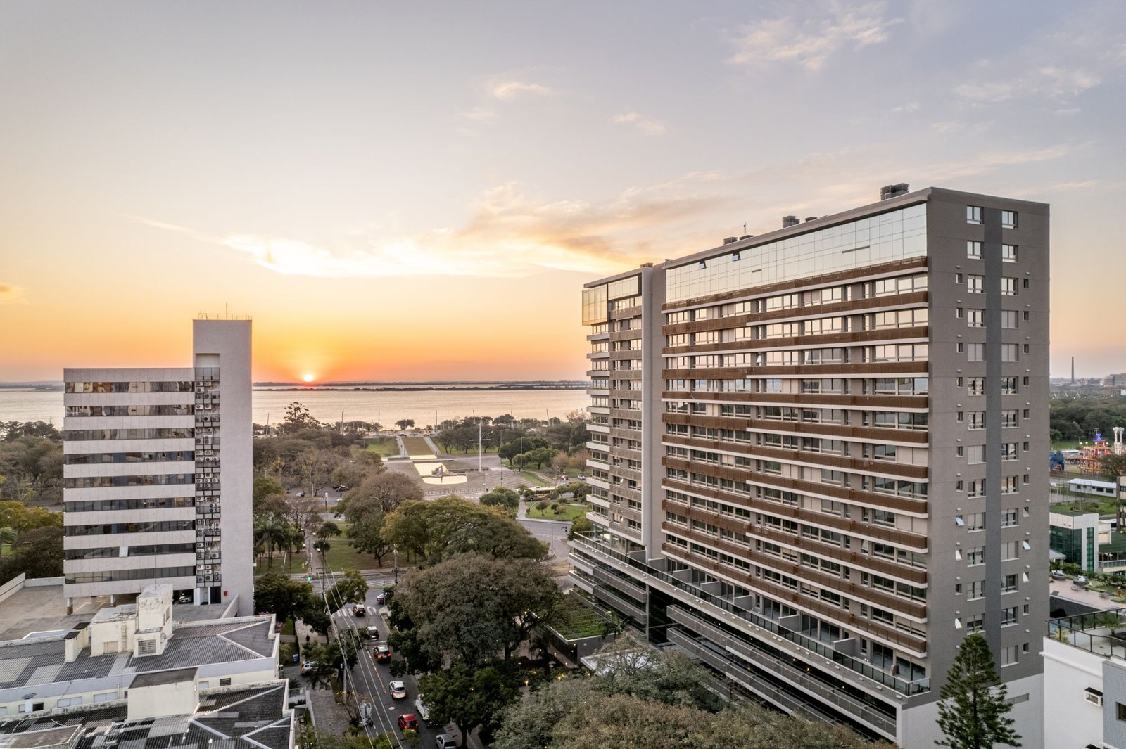 Edifício residencial em Porto Alegre ao entardecer, com o Guaíba ao fundo